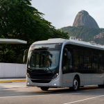 Ônibus elétrico urbano circula no Rio de Janeiro próximo a uma estrutura de transporte público.