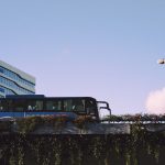 Ônibus moderno circula diante de um edifício envidraçado em uma área urbana.
