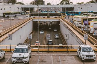 Ônibus e carros circulam por um viaduto movimentado em uma área urbana.