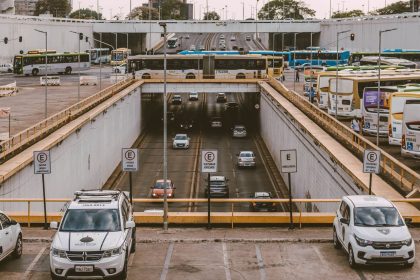 Ônibus e carros circulam por um viaduto movimentado em uma área urbana.