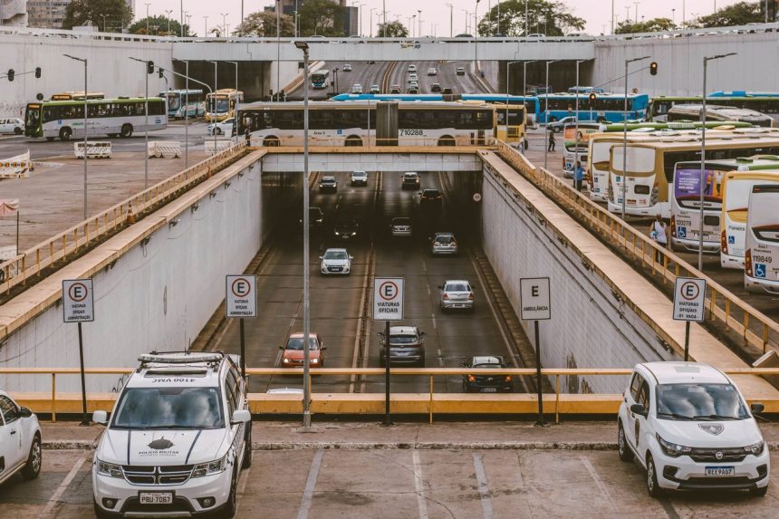 Ônibus e carros circulam por um viaduto movimentado em uma área urbana.