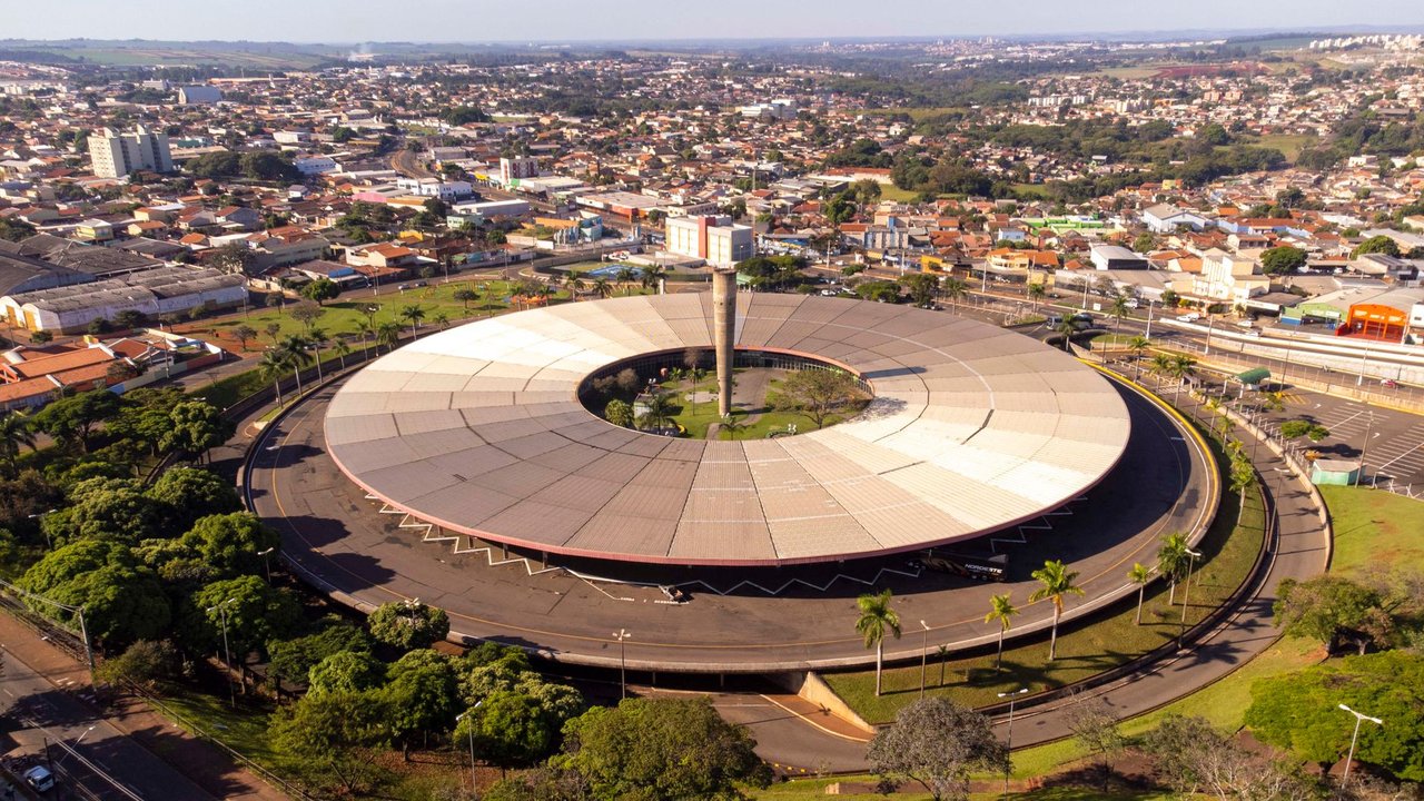 Vista aérea de um terminal rodoviário com ônibus, edifícios e a paisagem urbana ao redor